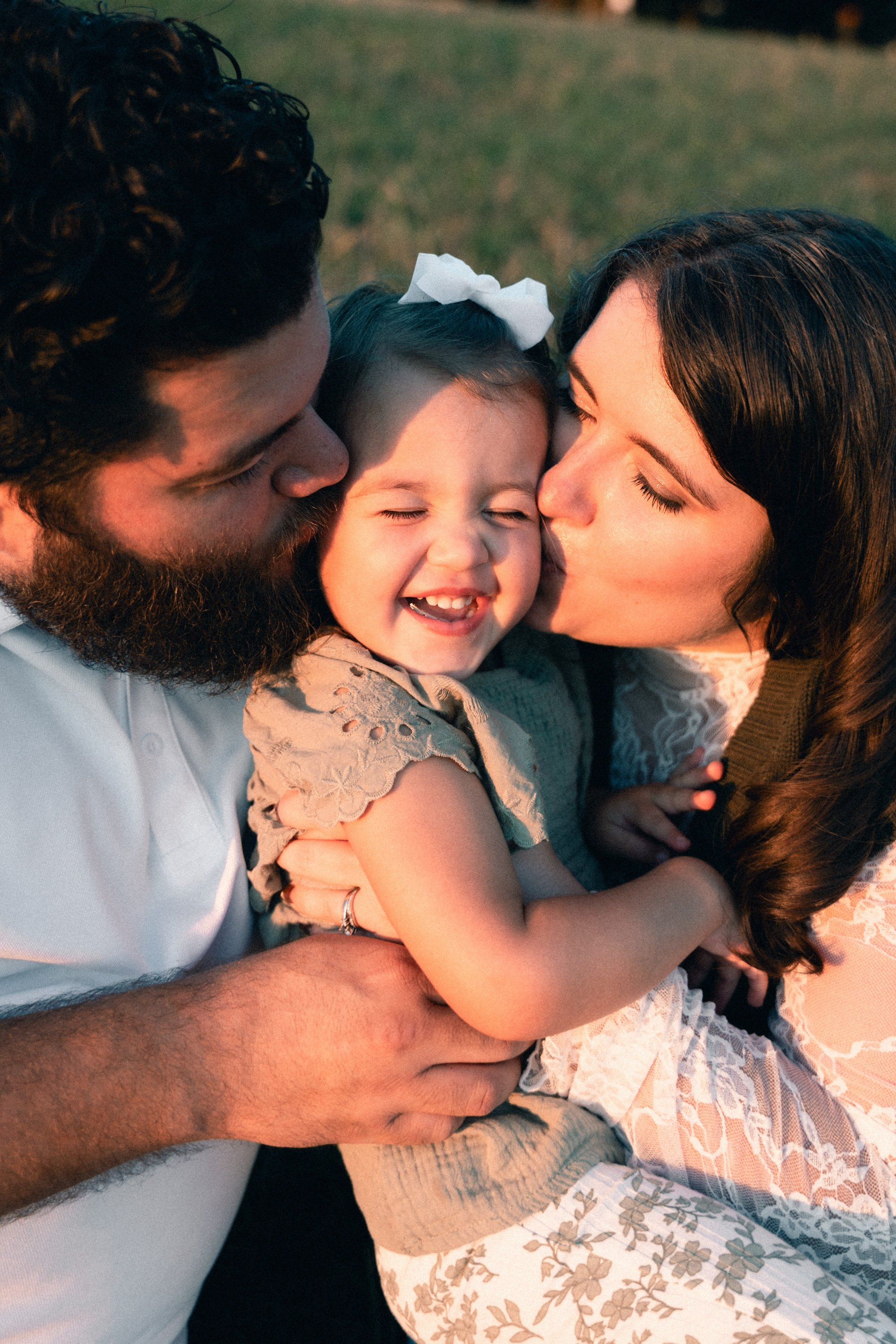 Parents kissing their daughter's cheeks