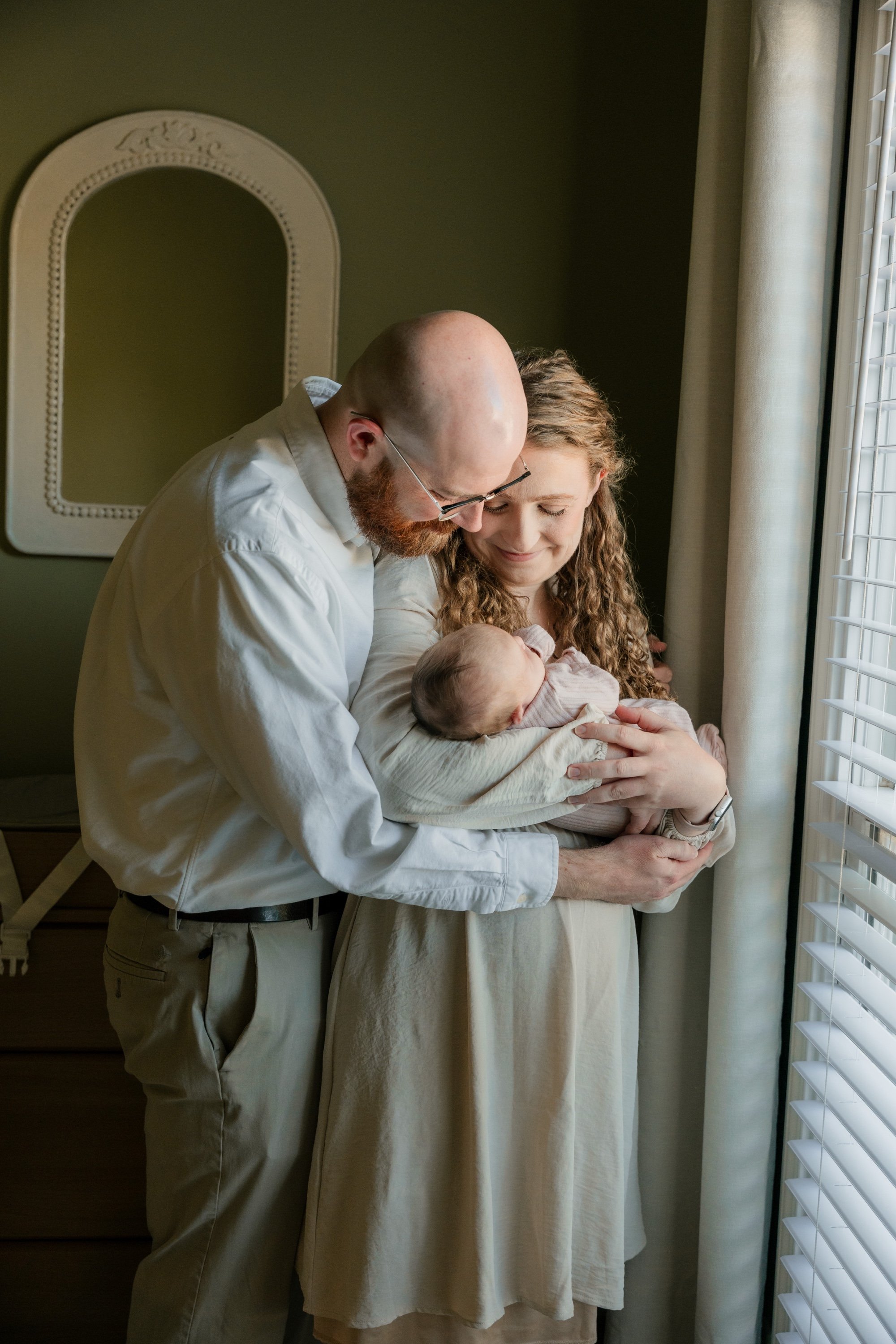 Parents holding their newborn by a window