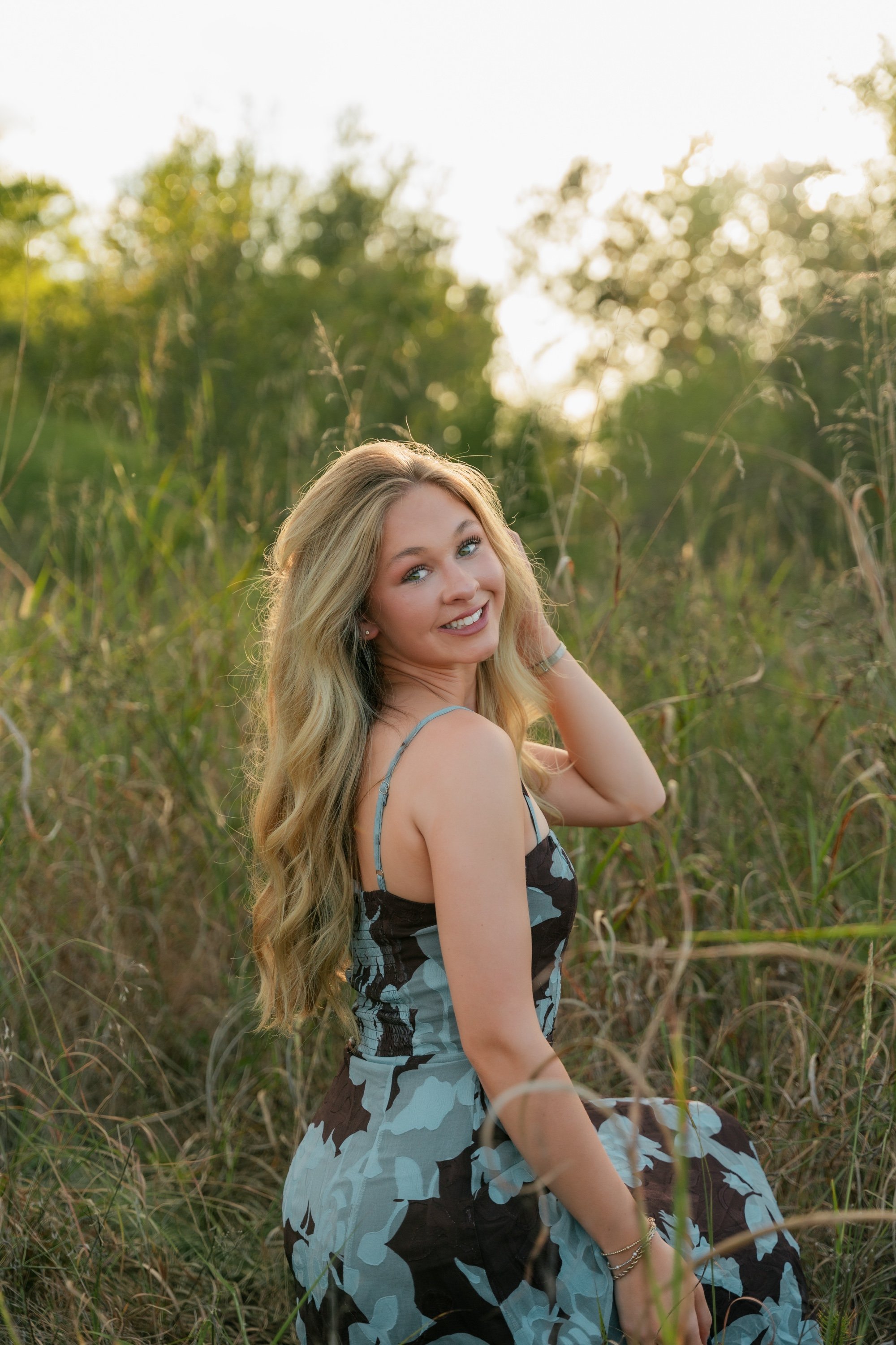 Senior smiling over her shoulder in tall grass